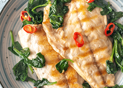 Omelet garnished with spinach and red chili slices served on a gray plate