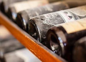 Bouteilles de vin poussiéreuses couchées sur un support de stockage en bois